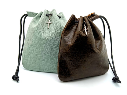 Two real leather rosary pouches, one in green and one in brown, each with a small crucifix and drawstrings.