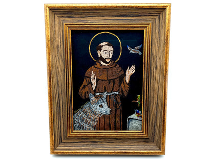 A framed religious icon depicting Saint Francis of Assisi with a brown robe, gold halo, blue-gray wolf, and a dove on a dark background, enclosed in a rustic wooden frame.