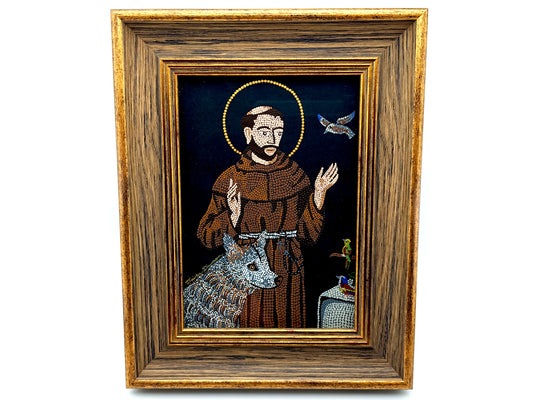 A framed religious icon depicting Saint Francis of Assisi with a brown robe, gold halo, blue-gray wolf, and a dove on a dark background, enclosed in a rustic wooden frame.