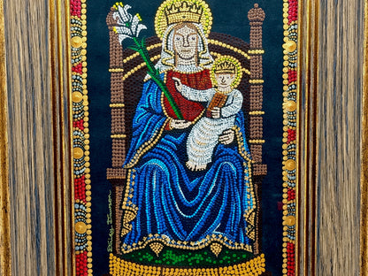 A framed religious mosaic artwork depicting the Madonna and Child on a dark background, with the mother in a blue robe and child in white, surrounded by ornate gold, red, and silver decorative borders.