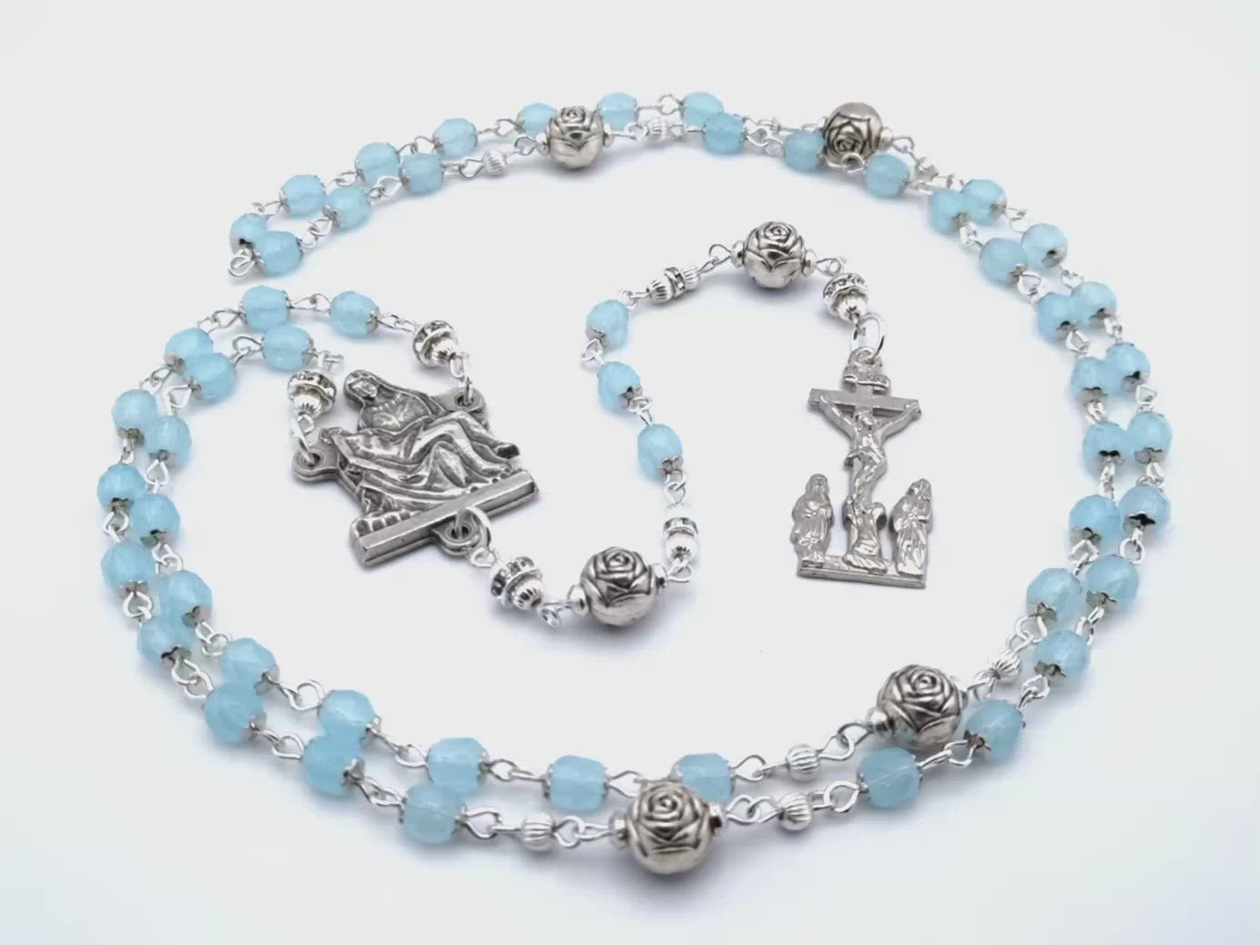 La Pieta unique rosary beads with pale blue glass and silver roses beads, silver two Marys crucifix and La Pieta centre medal.